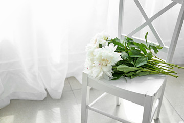 Bouquet of beautiful peony flowers on chair in room