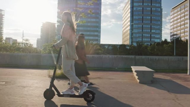 Young beautiful woman riding an electric scooter to work, modern girl, new generation, electric transport, ecology, ecological transport, sunset, electric skateboard, 4k