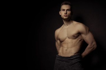 Fototapeta na wymiar Sexy stripped sport muscle guy with grey towel on vlack isolated font background