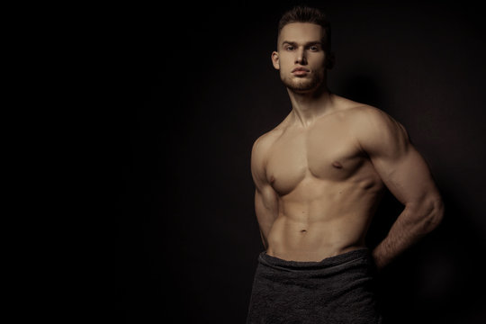 Sexy stripped sport muscle guy with grey towel on vlack isolated font background