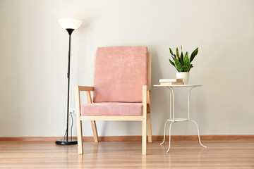 Armchair, table and lamp near light wall