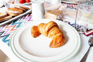 croissant in a plate on a table set for breakfast