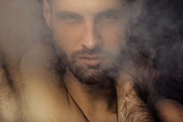 Handsome sport sexy stripped guy portrait in a water draps and fog smoke mist on isolated black...