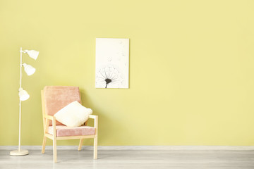 Fototapeta na wymiar Comfortable armchair and lamp near color wall with picture