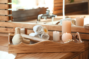 Tray with candles, sea salt, herbal bags and towels in spa salon