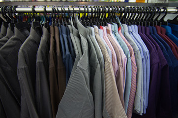 Colorful selection of clothes for men hanging on hangers in shopping mall for store sale concept