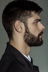 Obraz premium Muscle strong bearded face beautiful stripped male model in formal look with shirt and suit on grey isolated font background