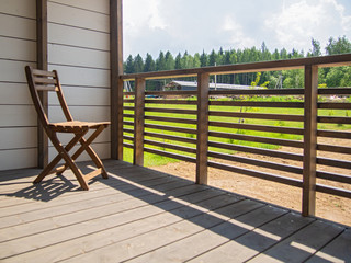 Country house terrace, hotel, garden wooden furniture, a chair. In the background is a green lawn. Horizontal orientation, space for text.