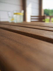 Garden furniture table and chair on the terrace of a country house, hotel. Two glasses with a refreshing drink with a lemon in the distance, blurred, on a wooden table. Focus on the tabletop.
