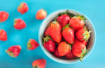 Juicy, ripe strawberries in a colorful turquoise bowl, top view