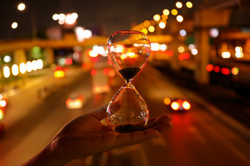Hourglass on a hand and traffic background, The concept of time