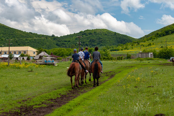 Four people on horses against the backdrop of highlands and beautiful cloudy sky.