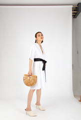 Asian Chinese Fashion influencer modeling in white dress with a tote bag isolated in white background