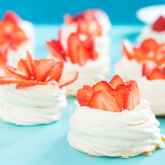Beautiful pavlova cakes with strawberries on a blue background. Selective focus. Tasty sweet breackfast. Wedding morning. Meringue with cream.