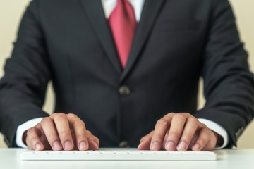 Close up hands of businessman wearing black suit typing wireless white keyboard. Header of business asian guy write email on computer pc in manager, executive or professional law people concept.