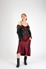 Asian Chinese Fashion influencer modeling in a wine color silk dress and leather jacket isolated in white background