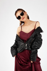 Asian Chinese Fashion influencer modeling in a wine color silk dress and leather jacket isolated in white background