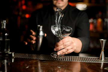 Bartender making a splash of the transparent alcohol in the cocktail glass