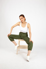 Asian Chinese Fashion influencer modeling in an army green pants and white tank isolated in white background