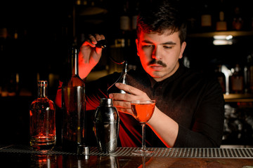 Male bartender spraying from the diffuser on the delicious cocktail in the glass
