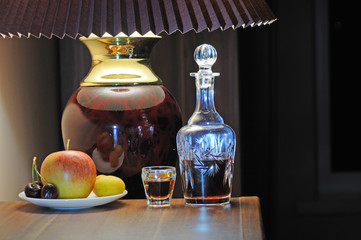 The decanter of whiskey, a stack of whiskey, a saucer with an apple, apricot and cherry under the...
