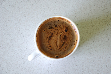 A cup of coffee with froth on a light background. View from above. Space for text and advertising.