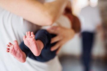 A mother holding a newborn baby at home, bare feet in the foreground.