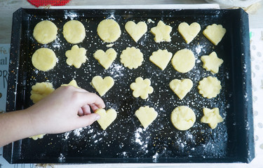 mano colocando una galleta con forma de coraz&oacute;n en una bandeja