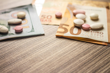 Fototapeta na wymiar Banknotes and medicines on a desk. Health cost concept. Money and drugs for legal use.