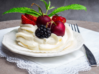 meringues pavlova cake with fresh cherry, blackberry, strawberry on concrete background
