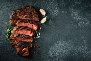 Tuinposter Sliced steak ribeye, grilled with pepper, garlic, salt and thyme on a dark stone background. Top view. Flat lay © Vasiliy