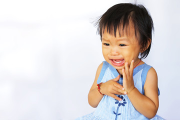 Asian baby child girl have a toothache. She crying and sad. Her hand touching her cheek. On a white background. Healthy dental care concept.