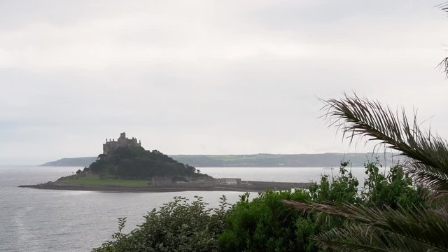 View from a terrace in Marazion of the english medieval castle and church of St Michael's Mount in Cornwall on a cloudy spring day. Zoom in 4k footage