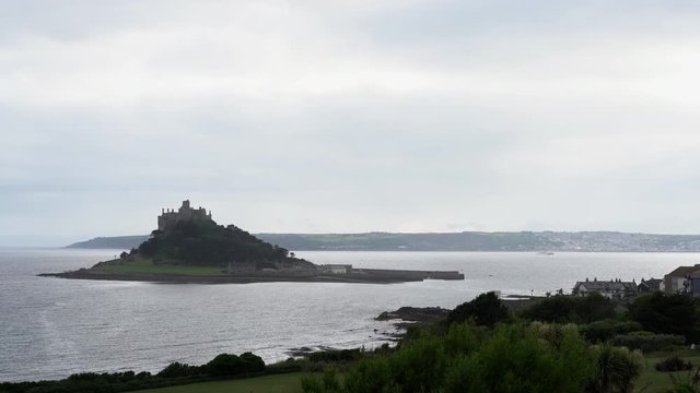 View from a terrace in Marazion of the english medieval castle and church of St Michael's Mount in Cornwall on a cloudy spring day.Zoom out 4k footage