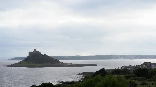 View from a terrace in Marazion of the english medieval castle and church of St Michael's Mount in Cornwall on a cloudy spring day. 4k footage
