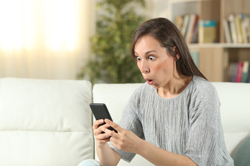 Fototapeta na wymiar Amazed woman at home checking smart phone