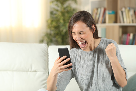 Excited woman at home checking smart phone