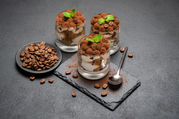 Classic tiramisu dessert in a glass on stone serving board on dark concrete background