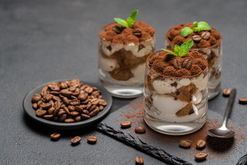 Classic tiramisu dessert in a glass on stone serving board on dark concrete background