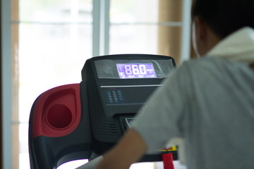 Young man running on a machine at home