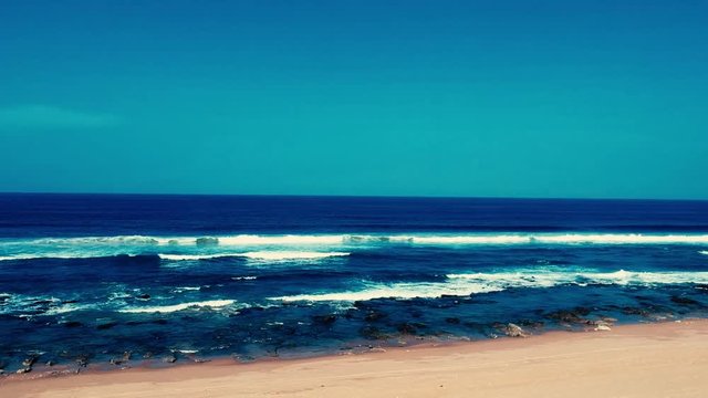 Aerial footage filmed with a drone overlooking the beach and sea of crashing waves with a deep blue ocean on the Bluff in Africa southern hemisphere.