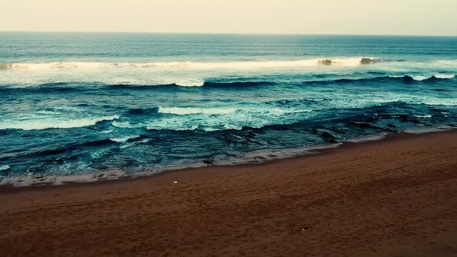Aerial footage filmed with a drone overlooking the beach and sea of crashing waves with a deep blue ocean on the Bluff in Africa southern hemisphere.