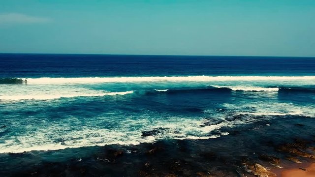 Aerial footage filmed with a drone overlooking the beach and sea of crashing waves with a deep blue ocean on the Bluff in Africa southern hemisphere.