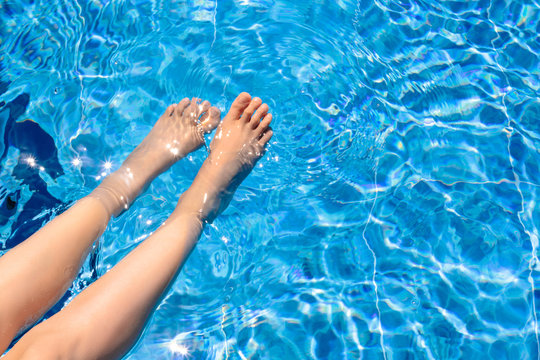 Relaxing in a pool Top view Girl with clean smooth skin is wetting feet in a pool with blue water Photo with copy space