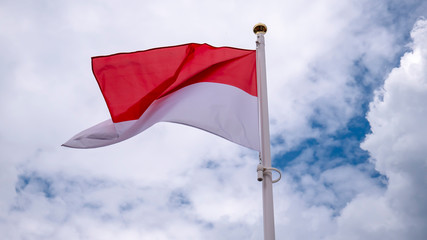Fototapeta na wymiar Polish flag flying against the blue sky with white clouds