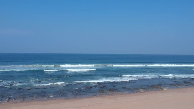 Aerial footage filmed with a drone overlooking the beach and sea of crashing waves with a deep blue ocean on the Bluff in Africa southern hemisphere.
