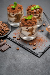 Classic tiramisu dessert in a glass on stone serving board on dark concrete background