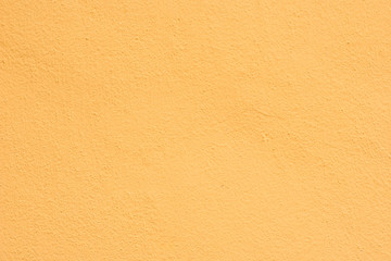 Background of a yellow stucco coated and painted exterior, rough cast of cement and concrete wall texture