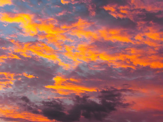 Dramatic sunset sky background with fiery clouds, yellow, orange and pink colors