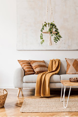 Modern boho interior of living room at cozy apartment with gray sofa, honey yellow pillows and plaid, plants, paintings, rattan basket and design personal accessories. Stylish home decor. Template. © FollowTheFlow